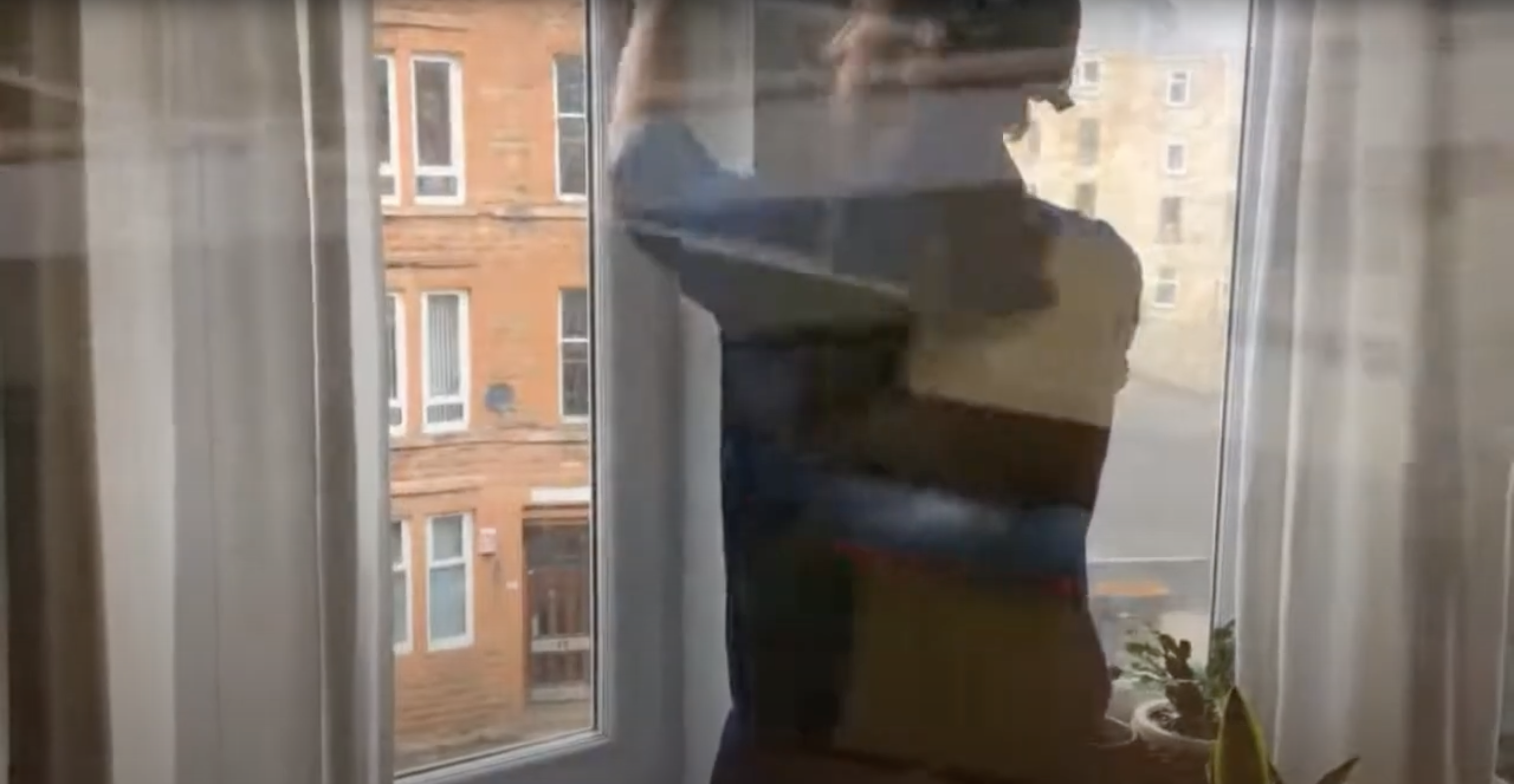An artistic still from a music video with a person opening a window.